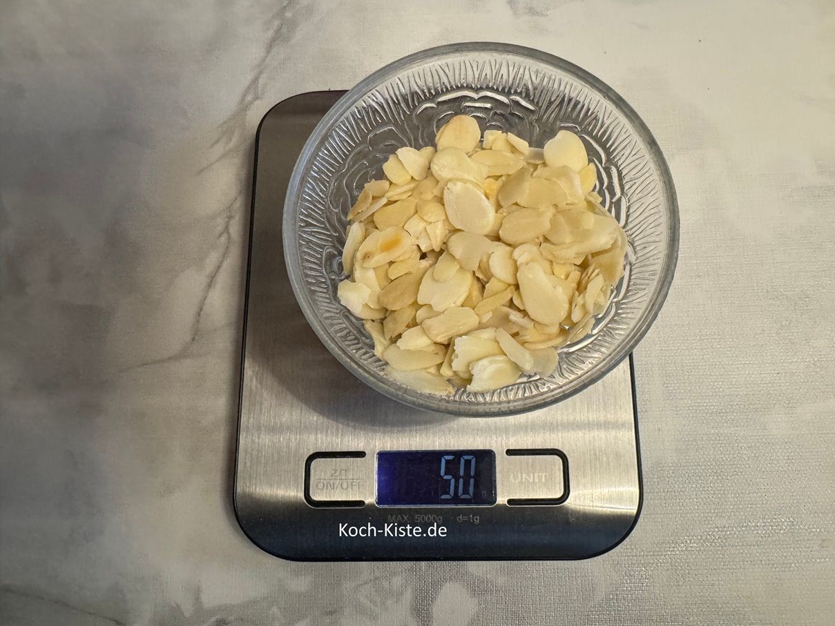 stelle eine kleine Schale auf die Küchenwaage und wiege 50g ( 100g) gehobelte Mandeln ab