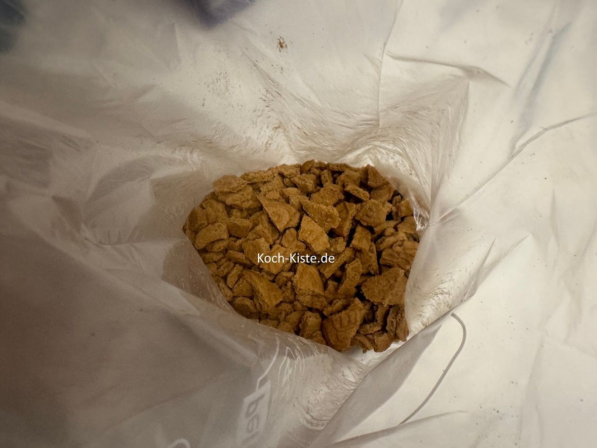 und zerdrücke sie mit einer Teigrolle zu kleinen Stücken/ Krümeln . Diese verteile auf den Boden