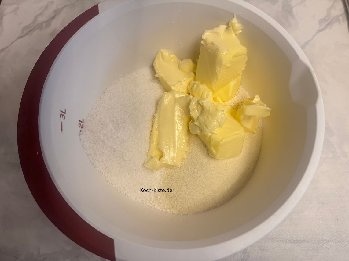 stelle die Küchenwaage zum 4 x auf 0 und schubse mit dem Schmiermesser 150 g weiche Butter in die Rührschüssel