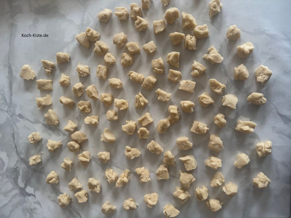 ziehe Dir erneut Vinyl Einmalhandschuhe an , nehme denTeig aus dem Kühlschrank und teile ihn nun in 5 g Portionen auf. Lege die abgewogenen Teigstücke auf die Arbeitsfläche