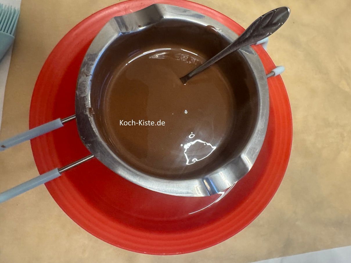 gieße das kochende Wasser vorsichtig in die Schüssel unter der Schmelzschale und rühre mit einem Teelöffel die Schokolade so lange, bis sie geschmolzen ist