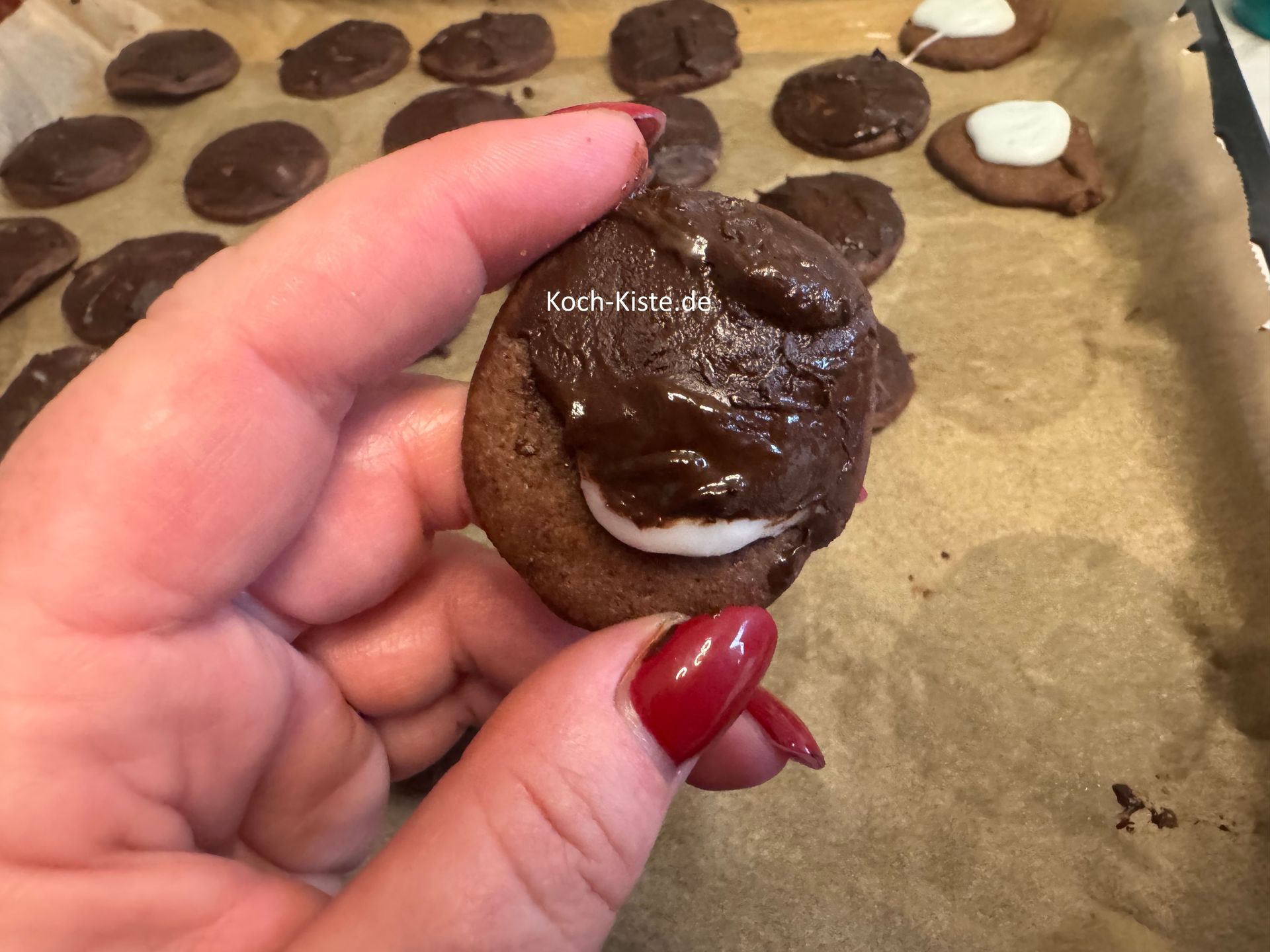 dann setze den Keks einmal ab und nehme ihn so in die Hand, dass Du an den freien Stellen die Kuvertürecreme auftragen kannst
