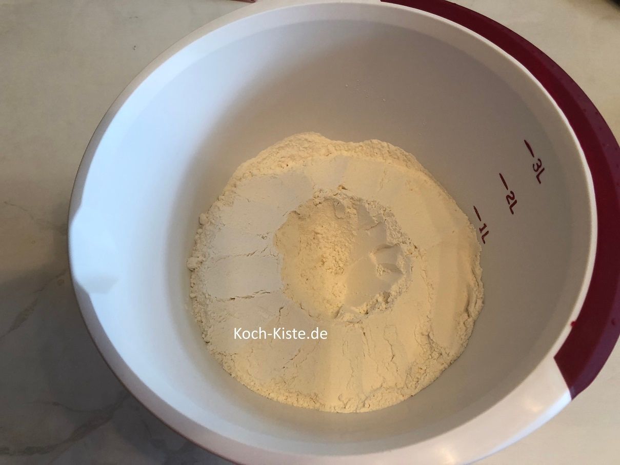beginne damit die Rührschüssel auf die Küchenwaage zu stellen auf 0 und die 500 g Dinkelmehl hinein zu wiegen. Dann forme mit einem Esslöffel eine Mulde in die Mehlmenge.
