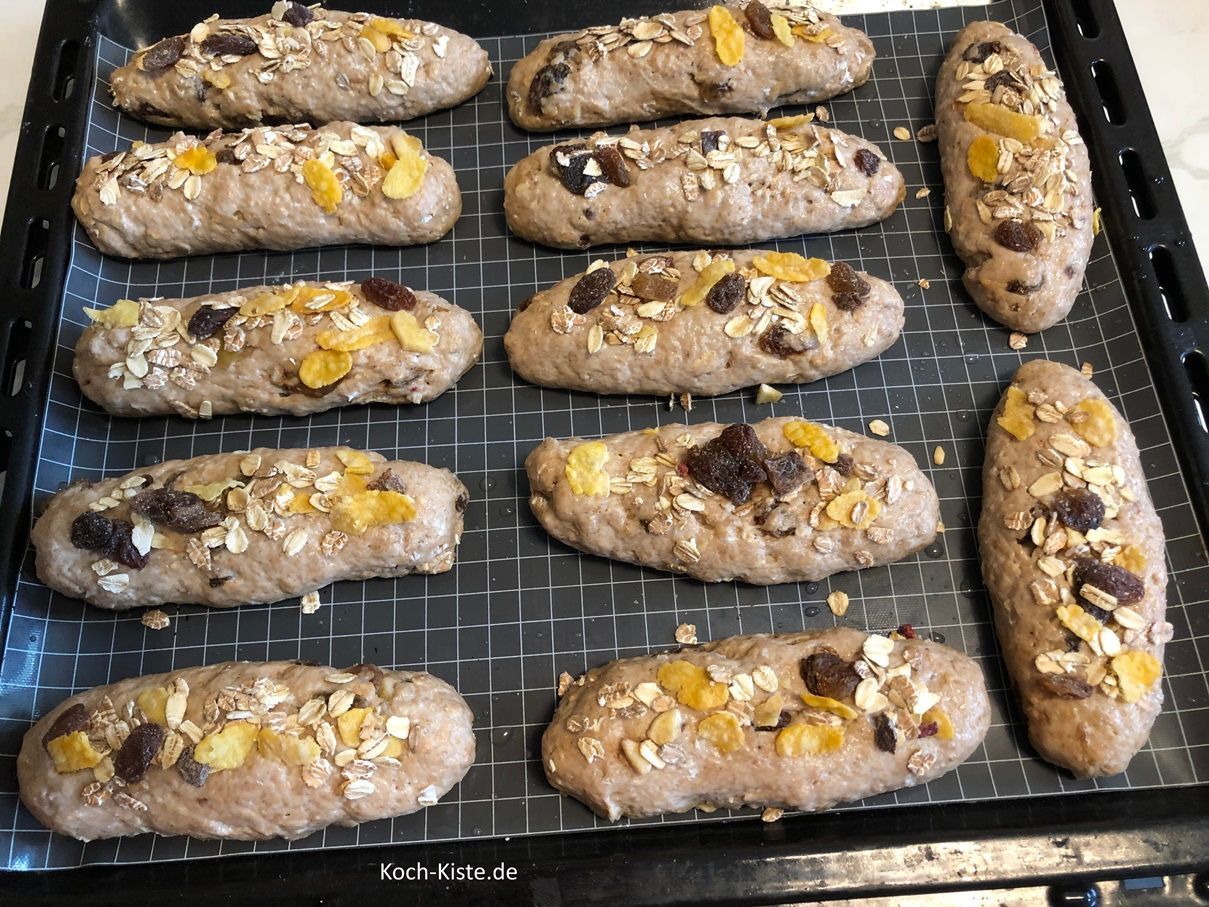 als nächstes bepinsel die Teigstangen nacheinander mit etwas Wasser und gebe etwas von den Müslikörnern oben auf. Drücke die Müsliteile leicht fest.