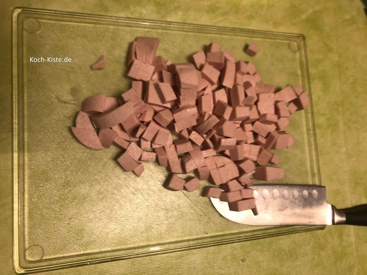 Fleischwurst in Scheiben, dann in kleine Stücke schneiden und in die Salatschüssel geben