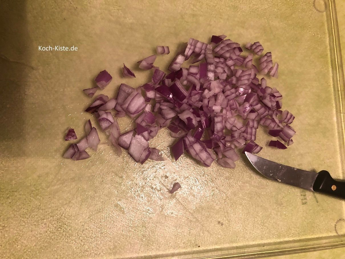 Zwiebel pellen, in kleine Würfel schneiden und in die Salatschüssel geben