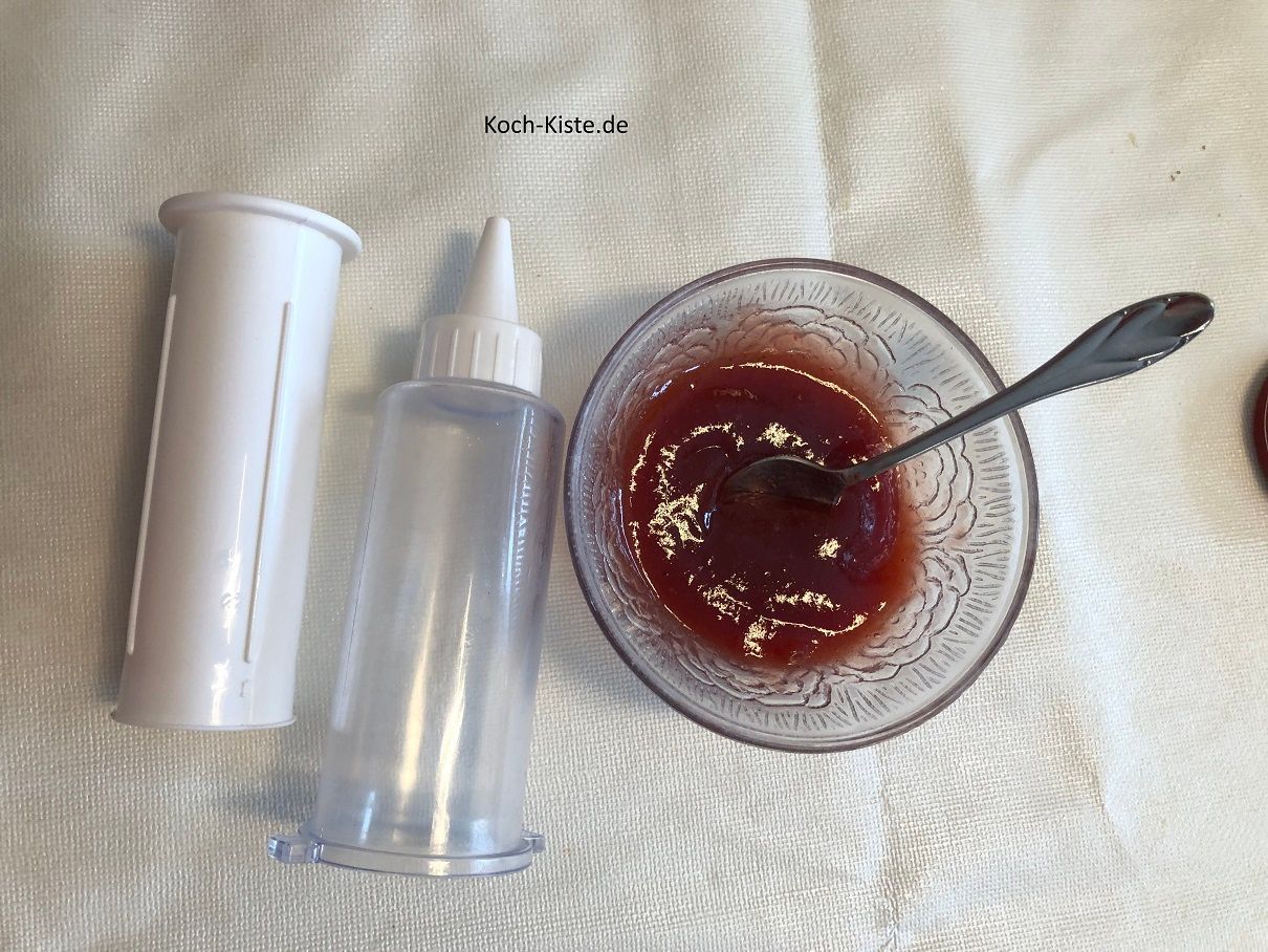 Lege Dir eine Gebäckpresse mit kleinster Lochtülle bereit. Gebe die Marmelade in eine kleine Schüssel und rühre sie glatt.
