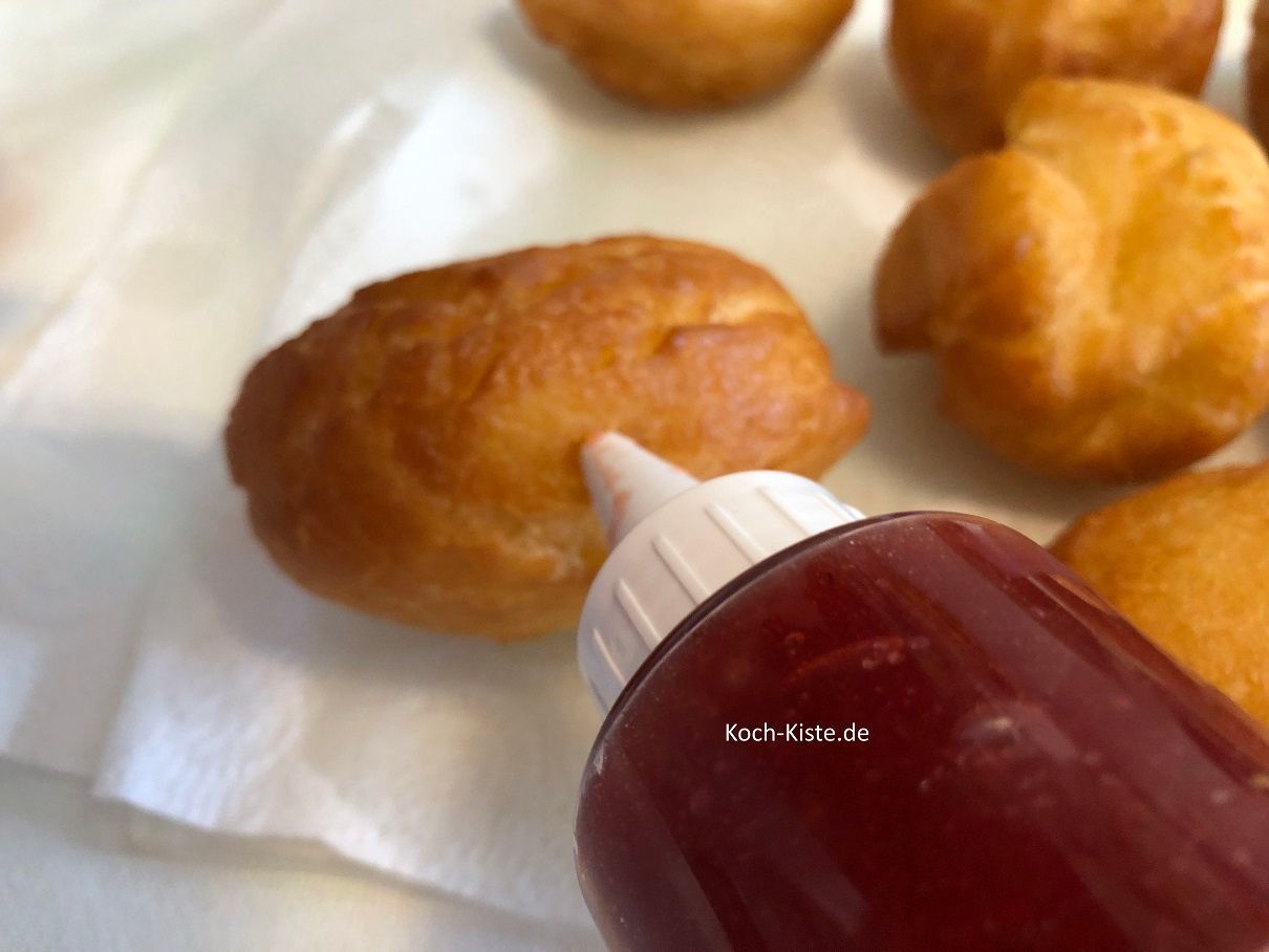 nehme Dir einen Berliner und führe die Lochspitze seitlich in den Berliner. Nun drücke etwas Marmelade in den Berliner.