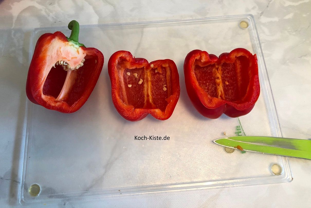 In der Zwischenzeit bearbeitest Du die Paprika. Erst halbieren , die Innenhäute heraus schneiden, die Kerne entfernen und unter kaltem, fließendem Wasser abspülen.