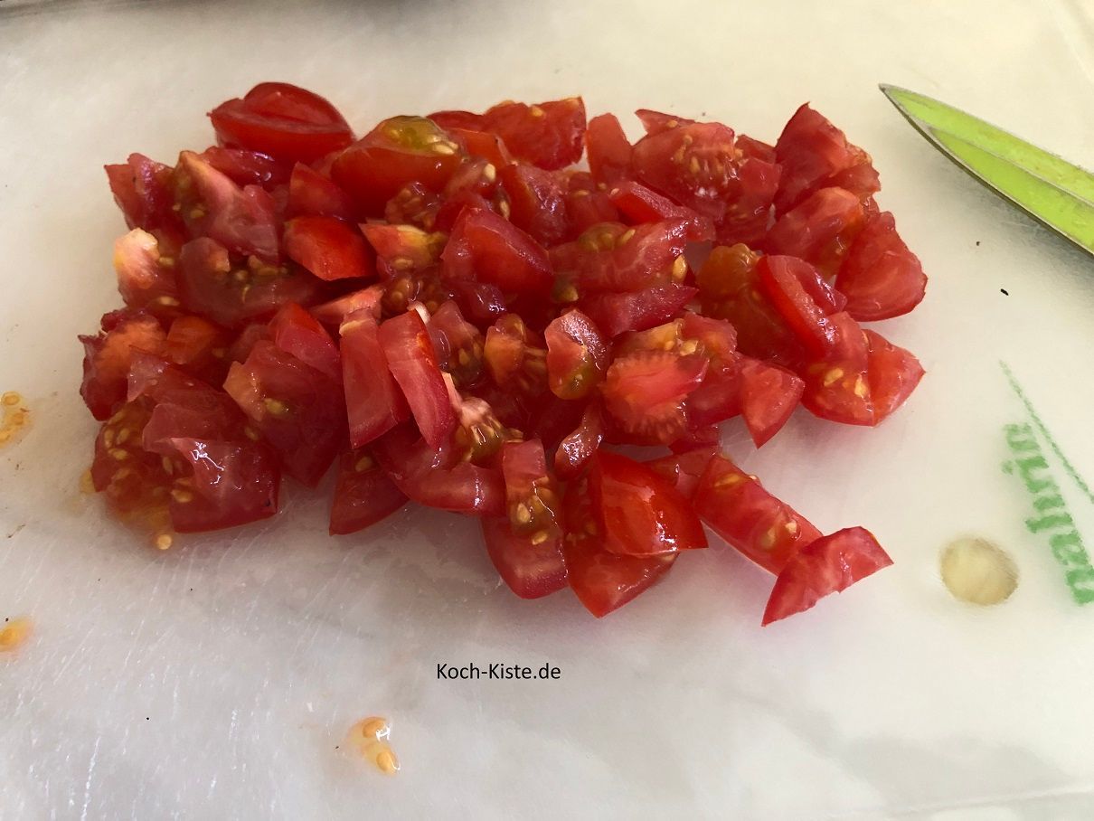 als nächstes halbiere die Tomaten, schneide den Stielansatz heraus und schneide die Tomaten in kleine Stücke