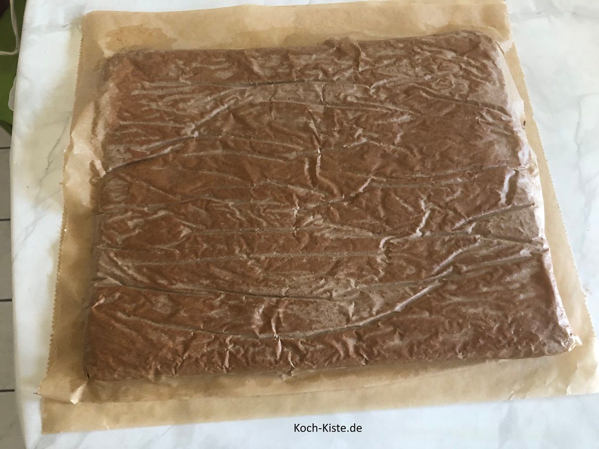 stürze den Bisquitboden auf ein Backpapier , welches auf der Arbeitsfläche liegt