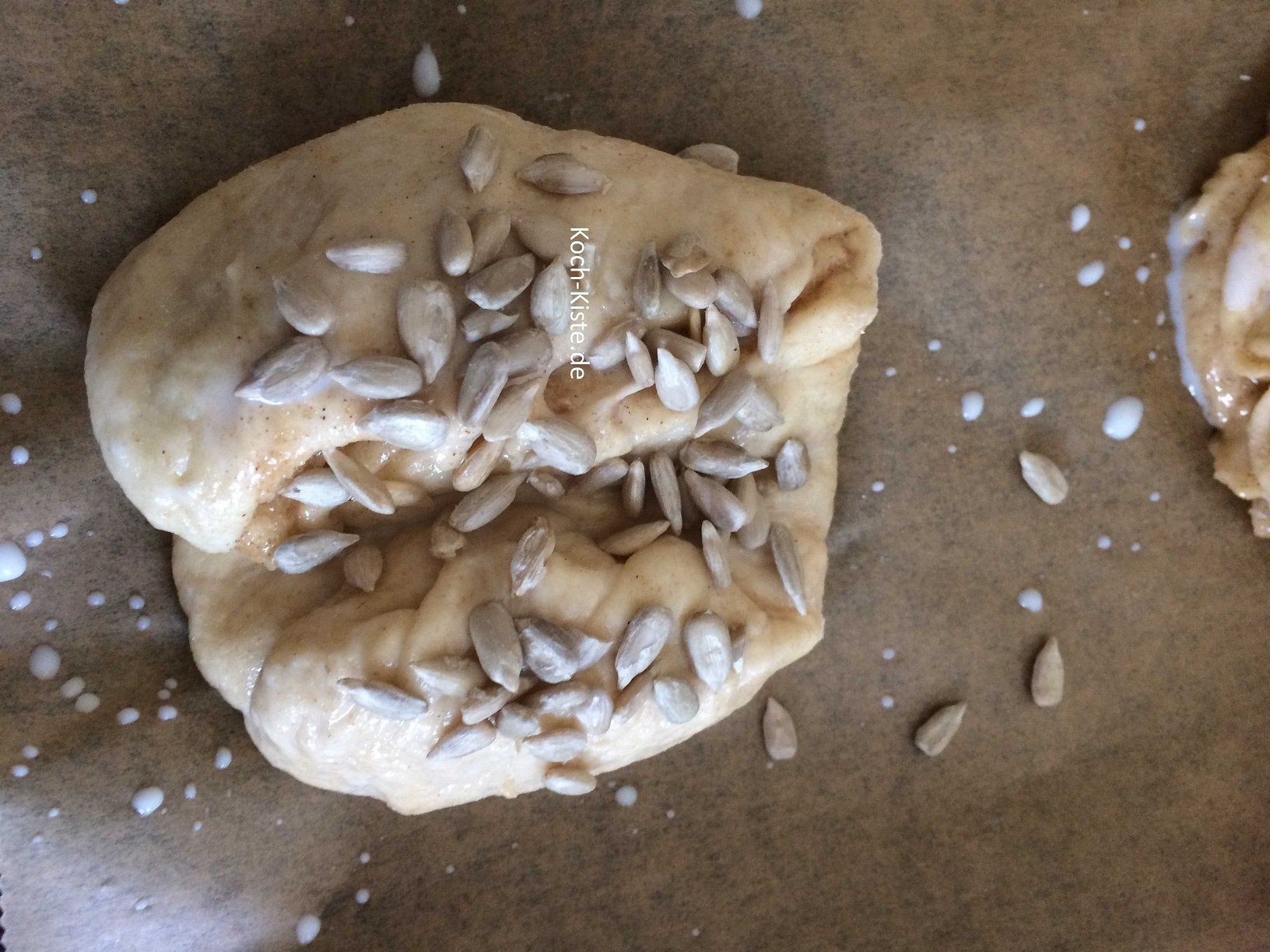 Franzbrötchen auf das Backblech legen, mit Milch bestreichen und mit Sonenblumenkerne bestreuen