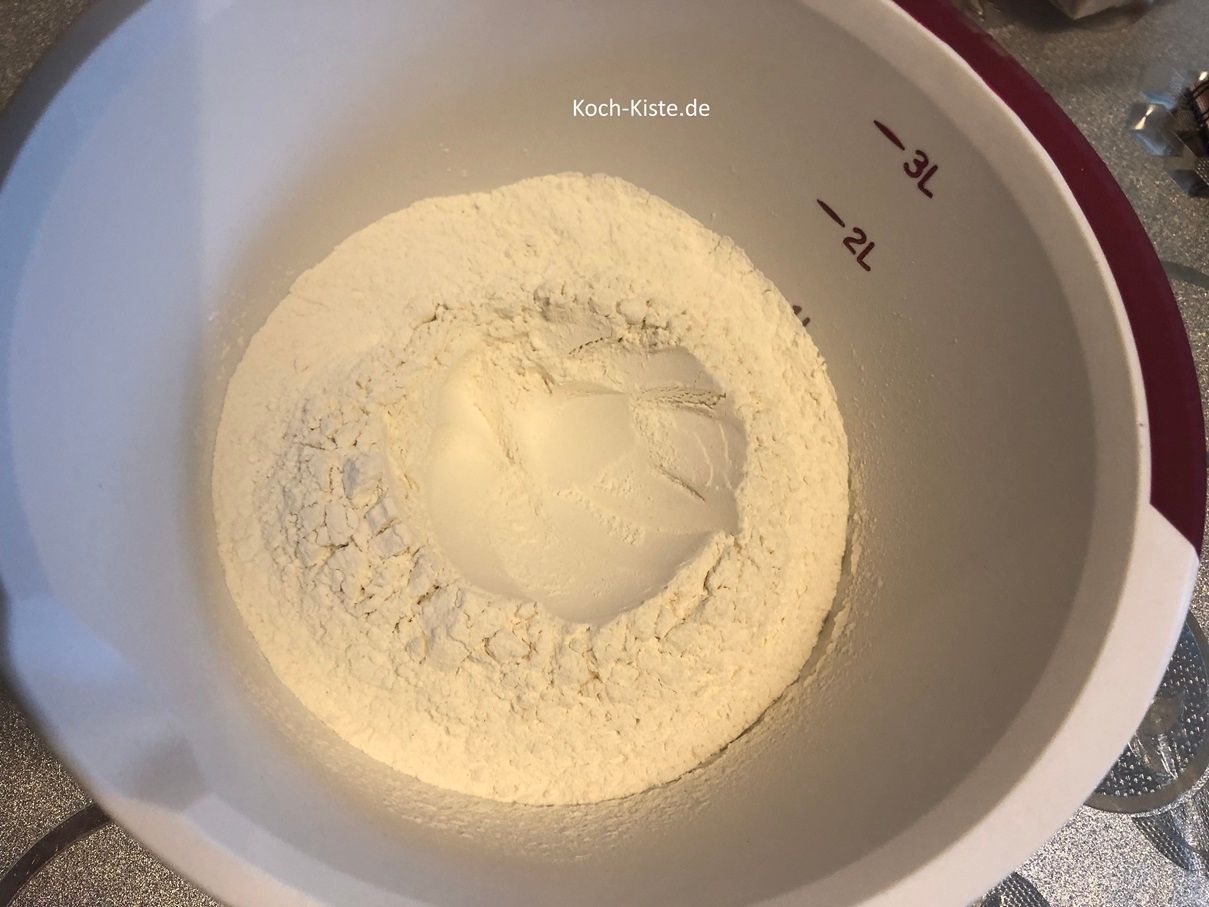 stelle die Rührschüssel auf die Küchenwaage auf 0 und wiege die benötigte Menge Dinkelmehl ab. Dann nehme einen Esslöffel und forme in die Mitte der Mehlmenge eine Vertiefung.
