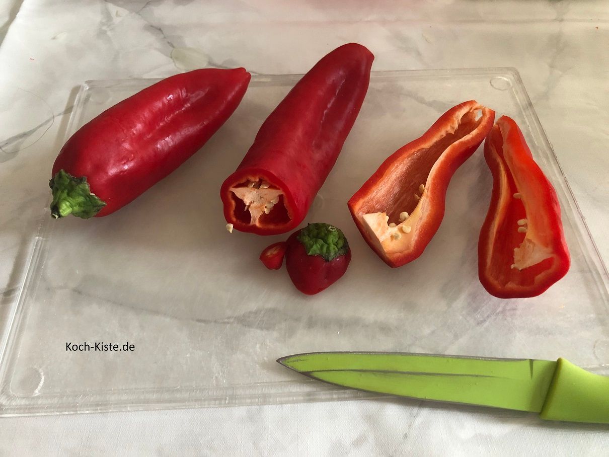 beginne damit bei den Spitzpaprikas je unten und oben ein Stück zu entfernen. Dann halbiere die Spitzpaprika