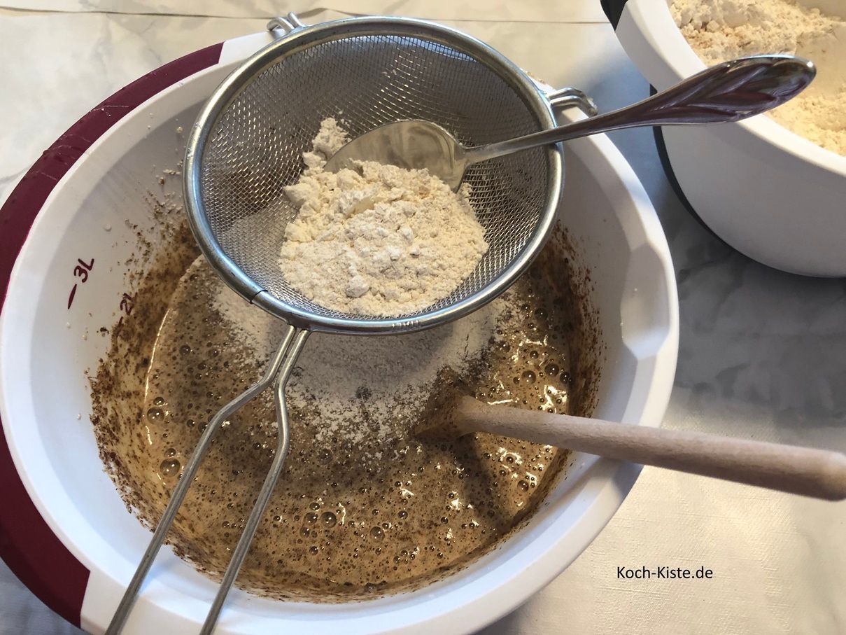 jetzt lege das Passiersieb auf die Rührschüssel und gebe nach und nach je 5 Esslöffel Dinkelmehl hinein. Mit dem Esslöffel streichst Du das Dinkelmehl hindurch, so dass das gesiebte Mehl in die Rührschüssel fällt.