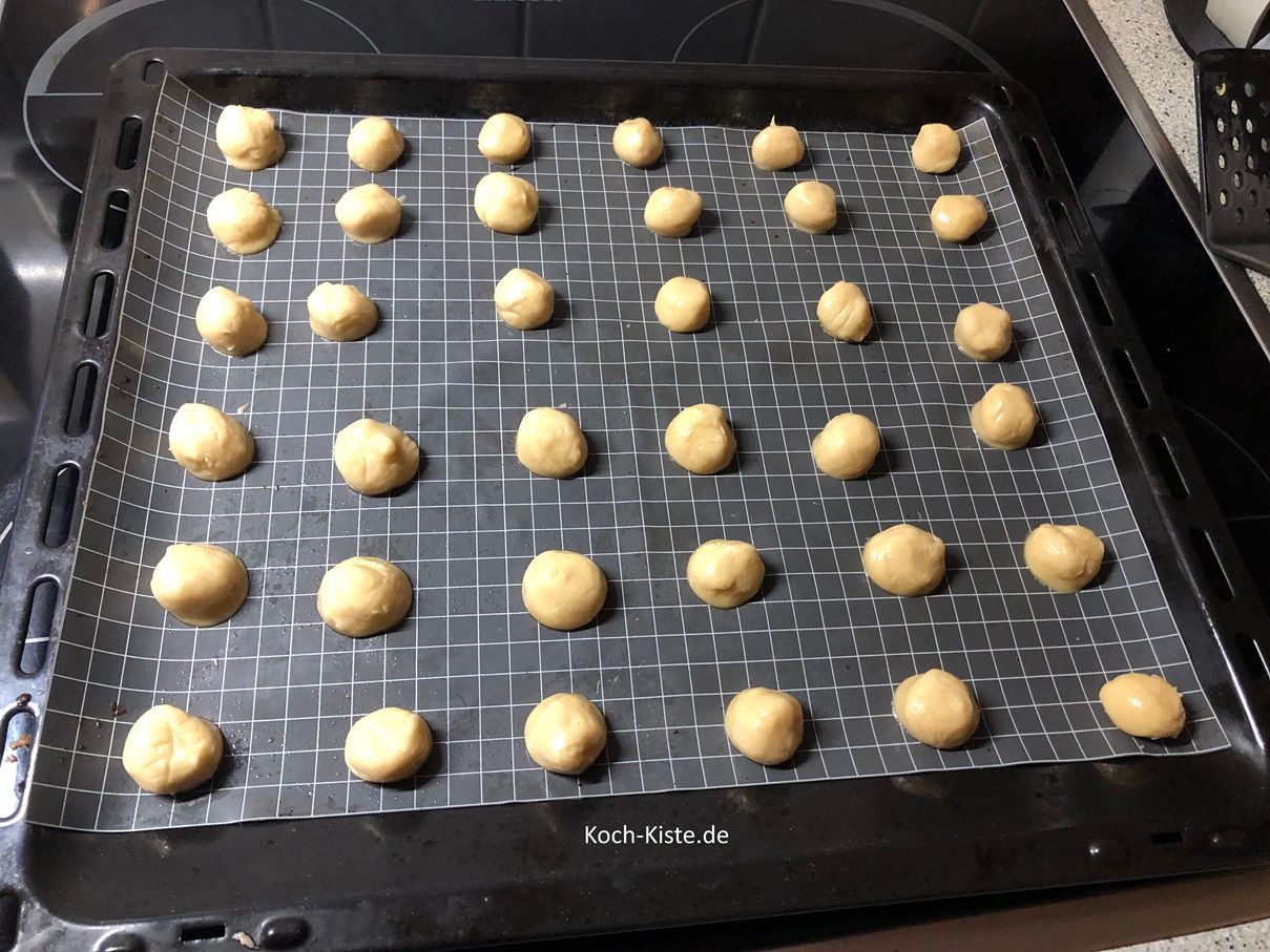 ziehe Dir Vinyl Einmalhandschuhe an und forme aus dem Teig kleine Kugeln. Diese müssen mit Abstand auf das Backblech gesetzt werden.