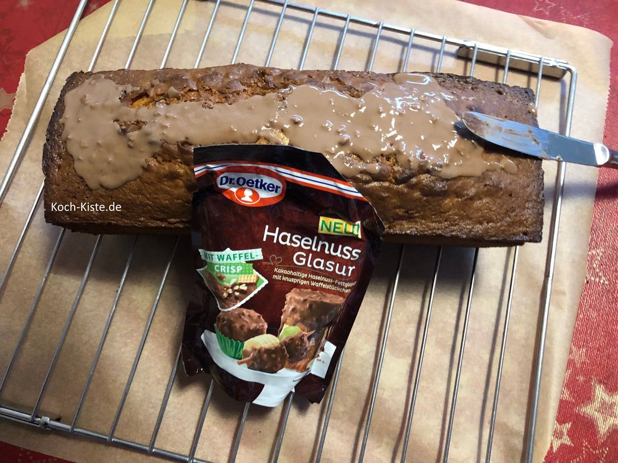 lege 1 Packung Schokoladenglasur deiner Wahl für 10 Minuten in heißes Wasser, damit die Schokolade weich wird. Dann gieße etwas der Schokoladenglasur auf die Oberseite des Kuchens.