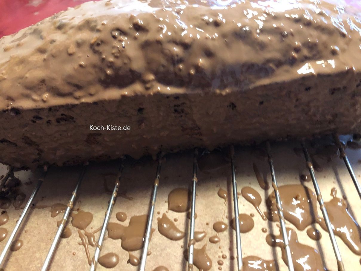 dann gebe die Schokoladenglasur auch auf die Kuchenseiten. Am einfachsten ist es mit der Teelöffelrückseite