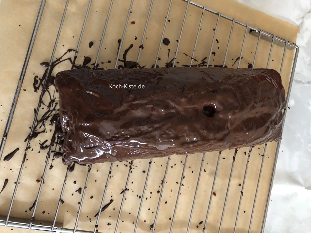 gebe zuerst oben auf den Kaffee-Kokos Kuchen die Schokoladenglasur und dann mit der Teelöffelrückseite auch an die Kuchenseiten