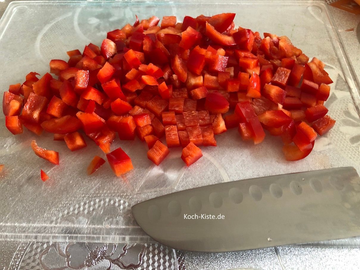 danach spüle die Paprika unter fließendem, kalten Wasser ab und lege sie wieder auf das Schneidebrett. Jetzt schneide die Paprika erst in Streife und dann in kleine Stücke