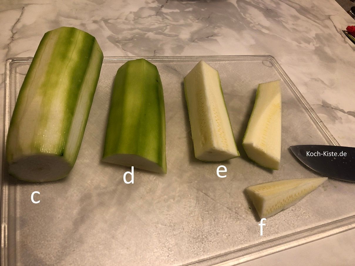 schneide die Zucchini eimal in der Mitte durch ( c) , dann halbiere sie der Länge nach (d) , viertel die Zucchini (e) und schneide etwas vom Kernstück heraus (f)