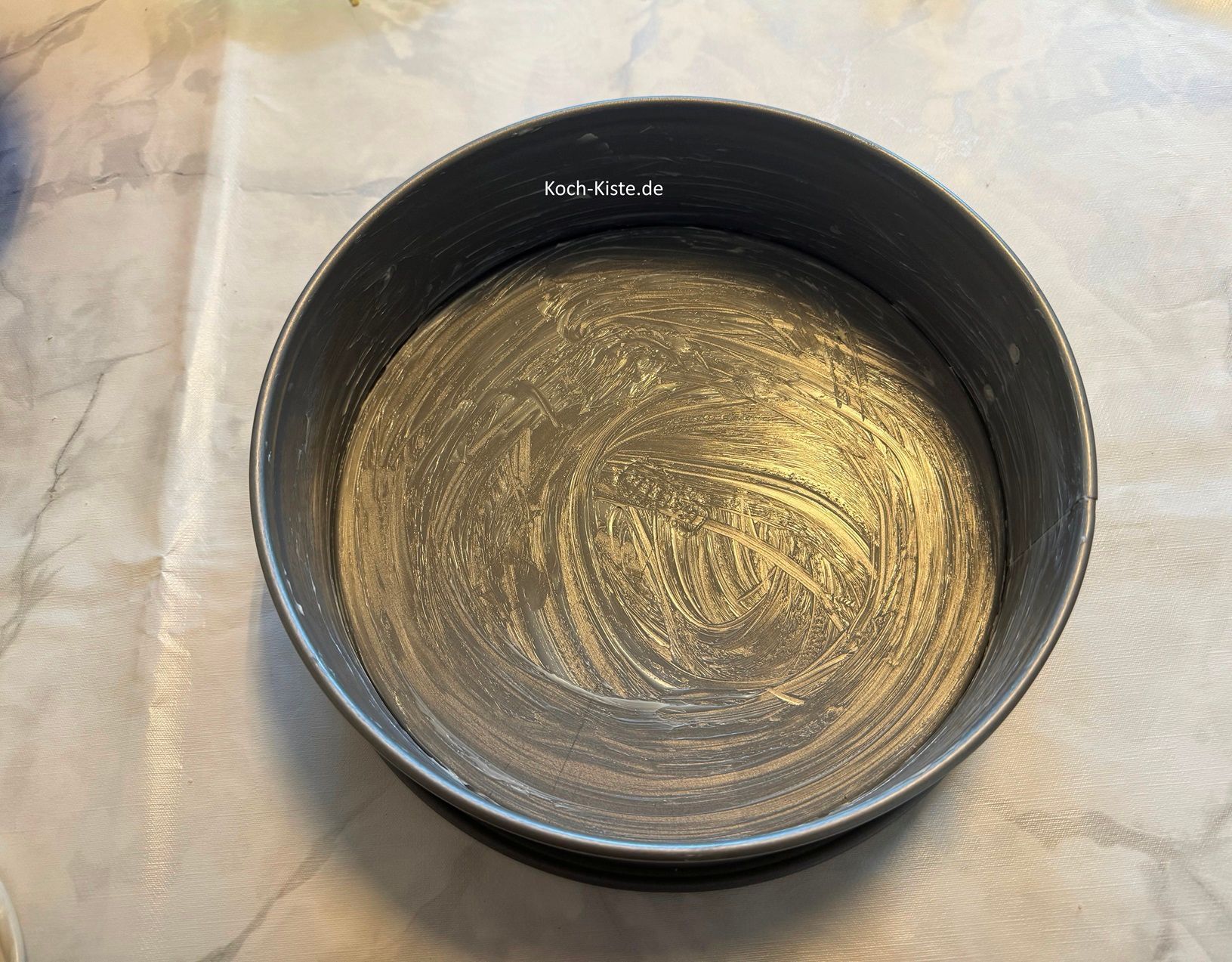 dann nehme ein Stück Backpapier, nehme etwas weiche Butter und fette die Springform ein.