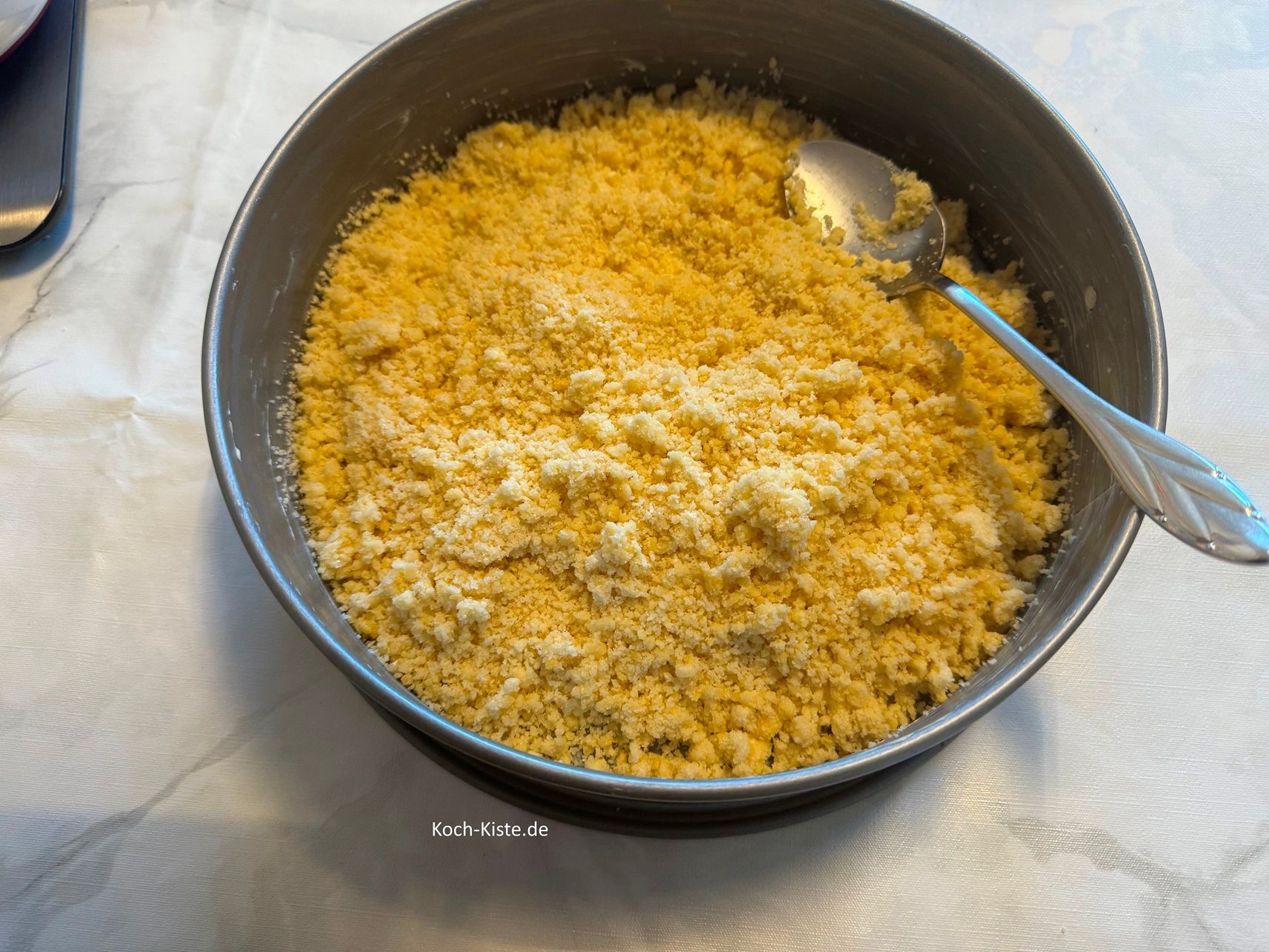 Nun kannst Du die 1/2 der Streusel in die Springform geben