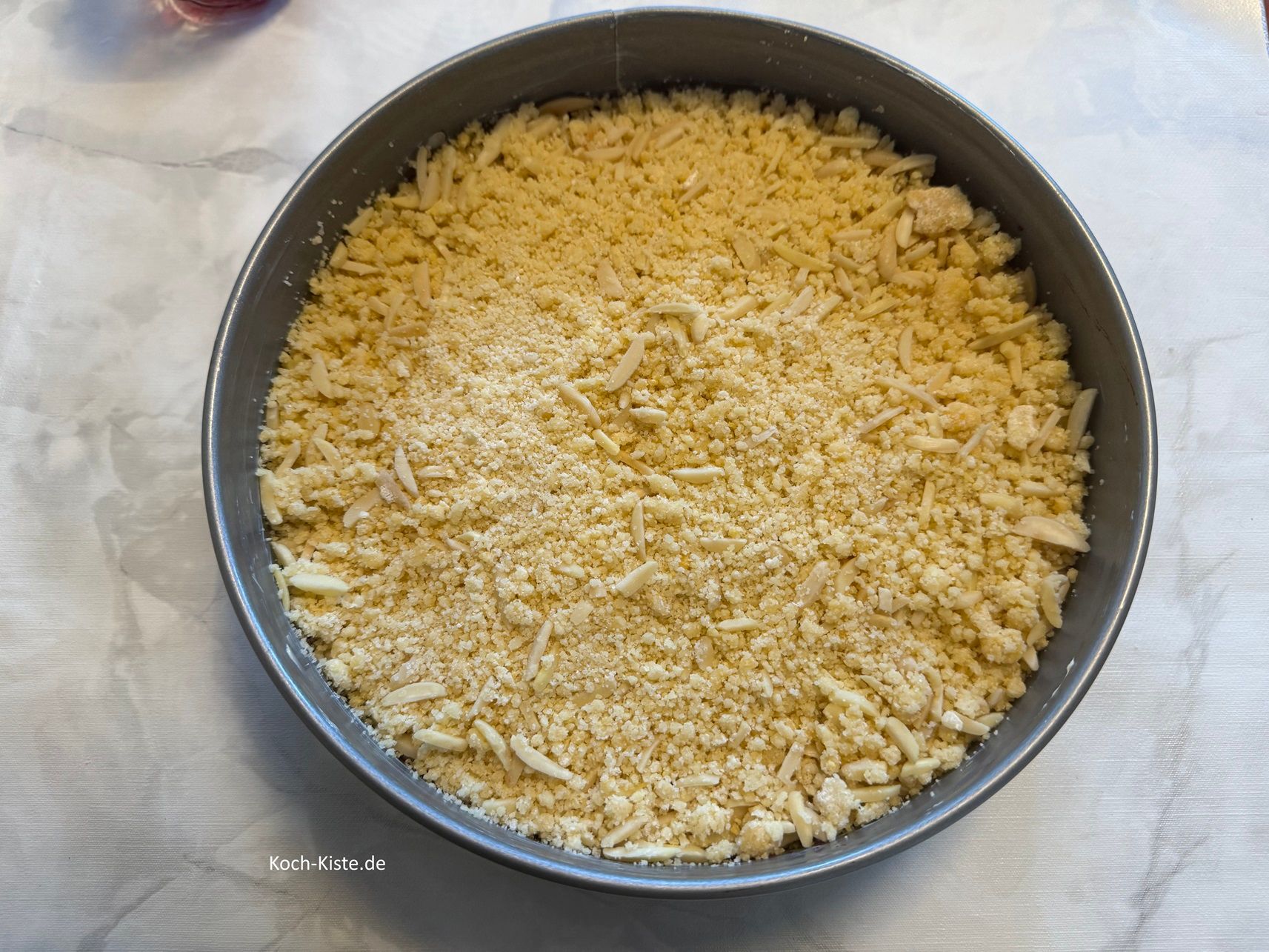 verteile die Streusel Mandelstiftmasse gleichmäßig auf der Marmeladenschicht