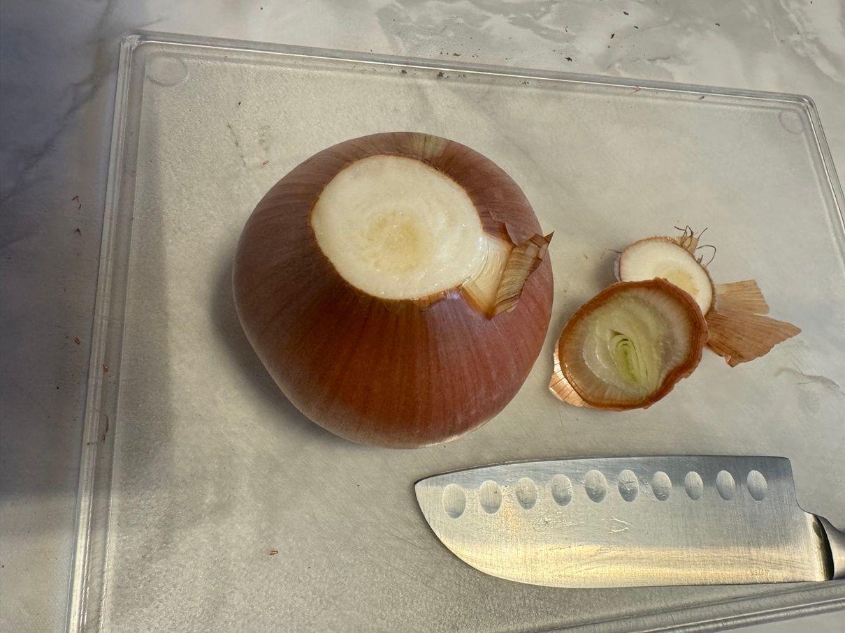 beginne damit die Füllzwiebel auf das Schneidebrett zu legen und oben und unten ein Stück zu entfernen