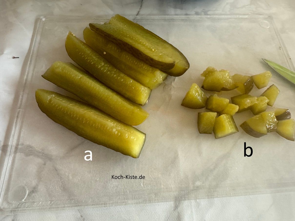 Als nächstes lege Dir mit Hilfe der Gabel immer einige Grukenstiks auf das Schneidebrett, halbiere sie (a) und schneide sie in kleine Stücke (b).