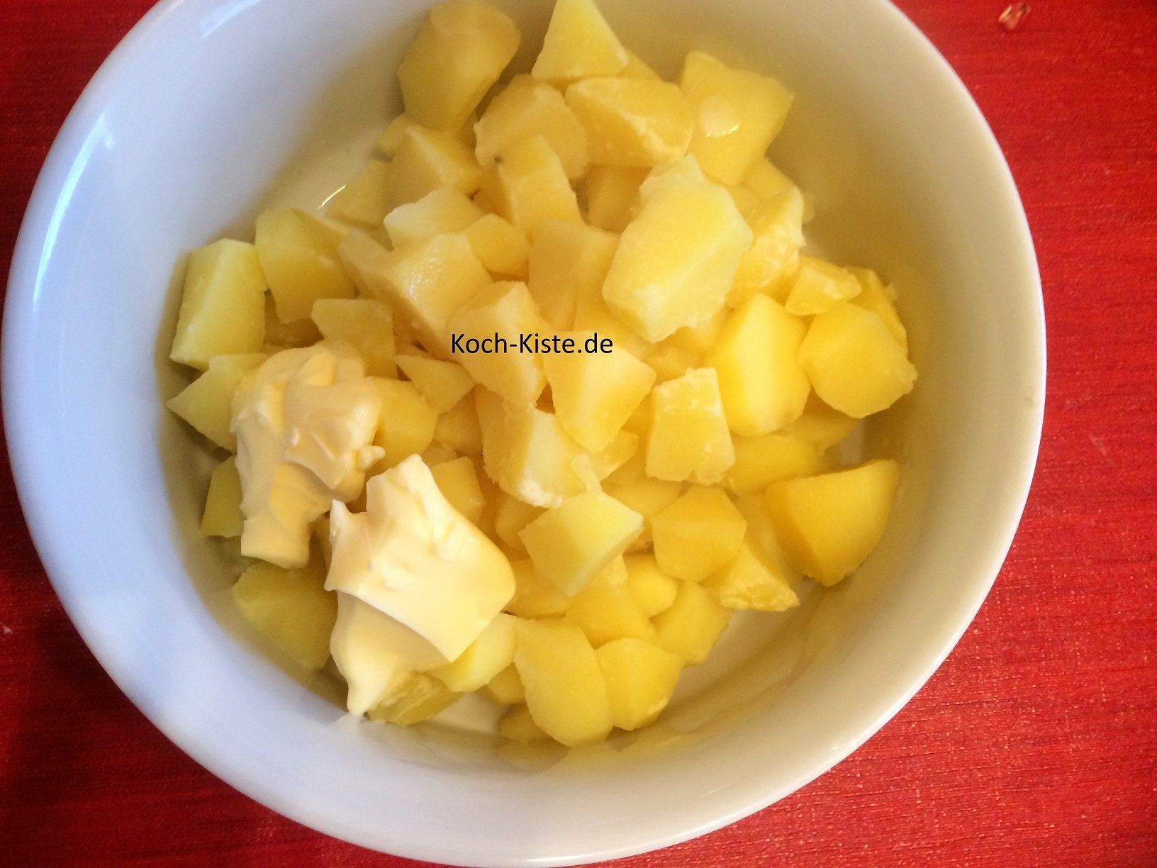 Butter und Milch zu den Kartoffeln geben