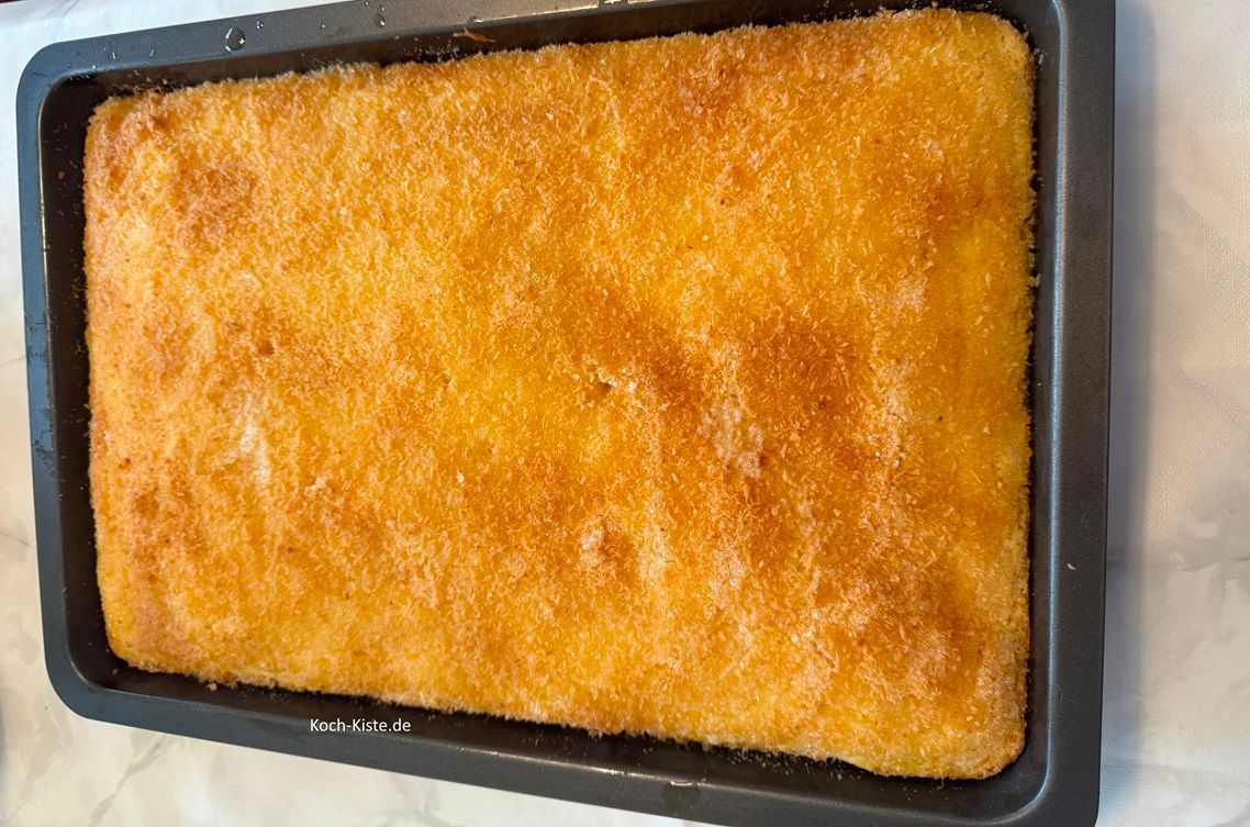 verteile mit Hilfe eines Esslöffels die geschmolzene Butter gleichmäßig auf den Kokos Blechkuchen