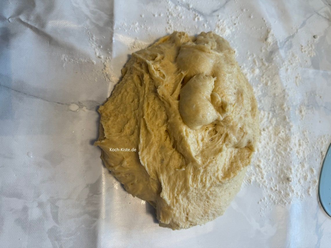 bemehle die Arbeitsfläche etwas und schubse den Teig aus der Knetschüssel. Dann knete den Teig noch mal kurz durch.