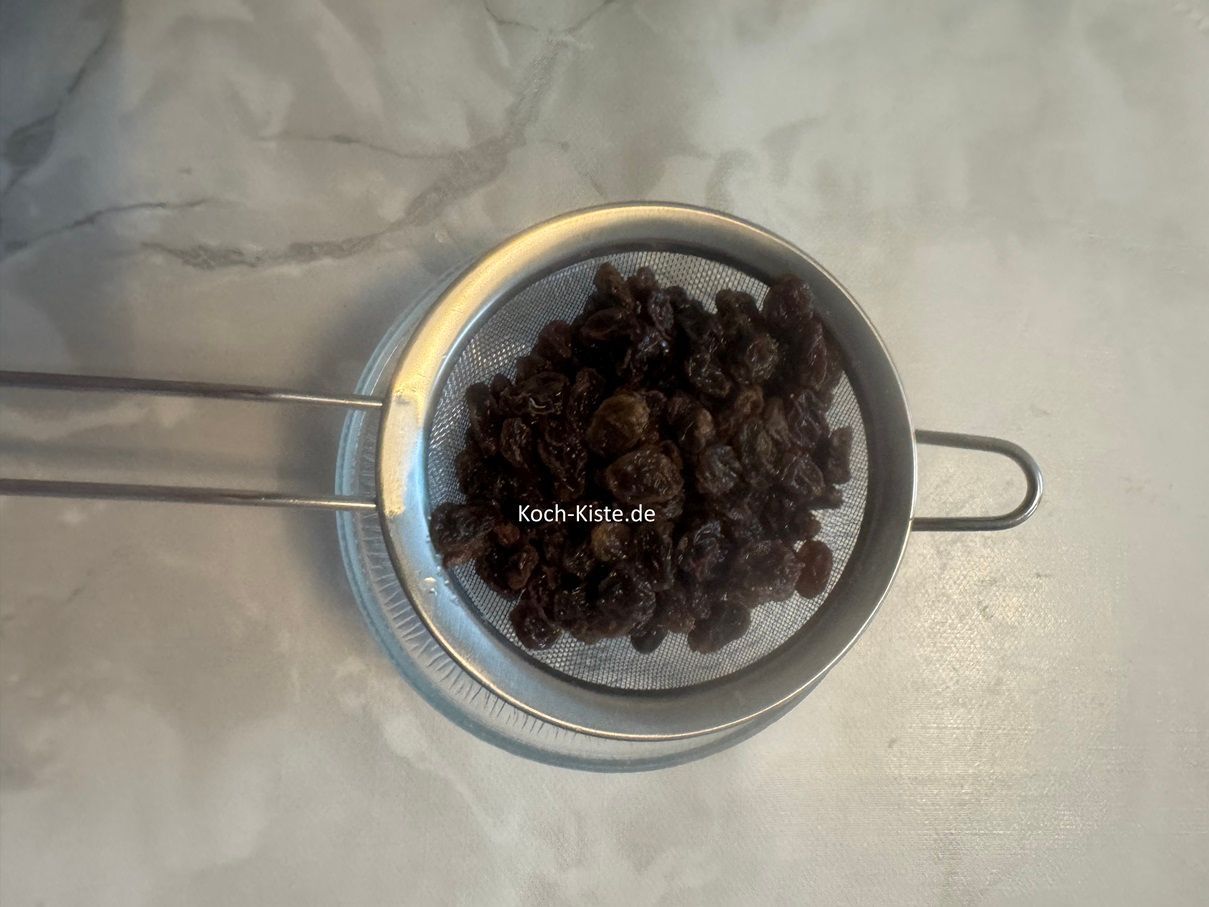 nehme ein mittleres Haarsieb und halte es über die Küchenspüle, nun schütte die Rosinen hinein, so dass das ablaufende Wasser in die Spüle läuft. Lege das Küchensieb auf eine kleine Schale und lasse die Rosinein vollständig abtropfen.