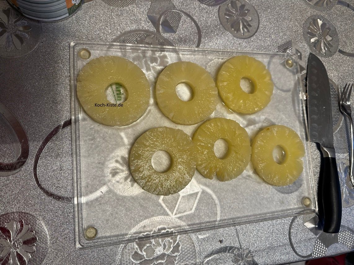 Hebe mit einer Gabel einiger der Annanasringe auf das Schneidebrett