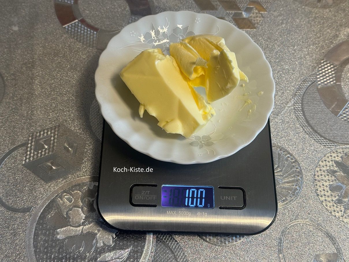 Für die Butter stelle einen kleinen Teller auf die Küchenwaage auf 0 und schubse mit einem Tafelmesser 100g weiche Butter auf den Teller