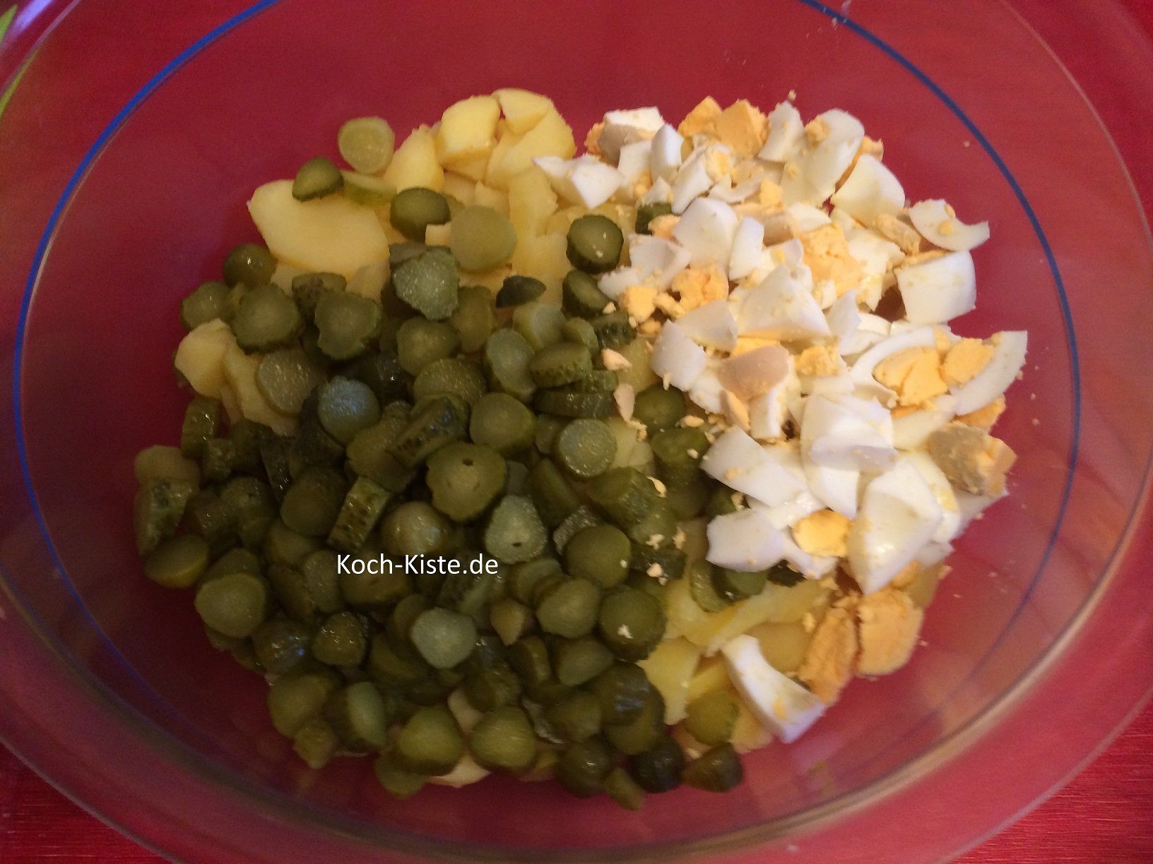 Cornicons mit in die Salatschüssel schneiden und Eierstücke hinzugeben