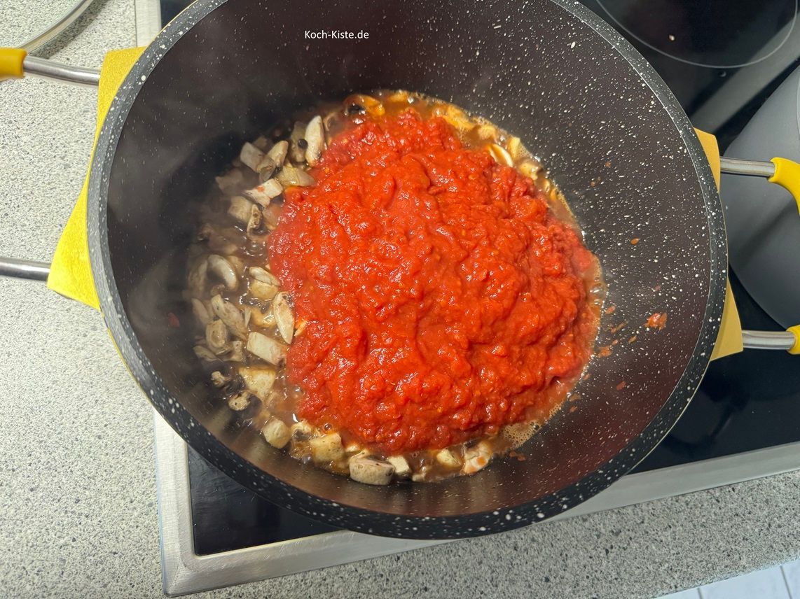 als nächstes kommen 2 Packungen gehackte Tomaten und 100 ml Wasser mit in den Topf