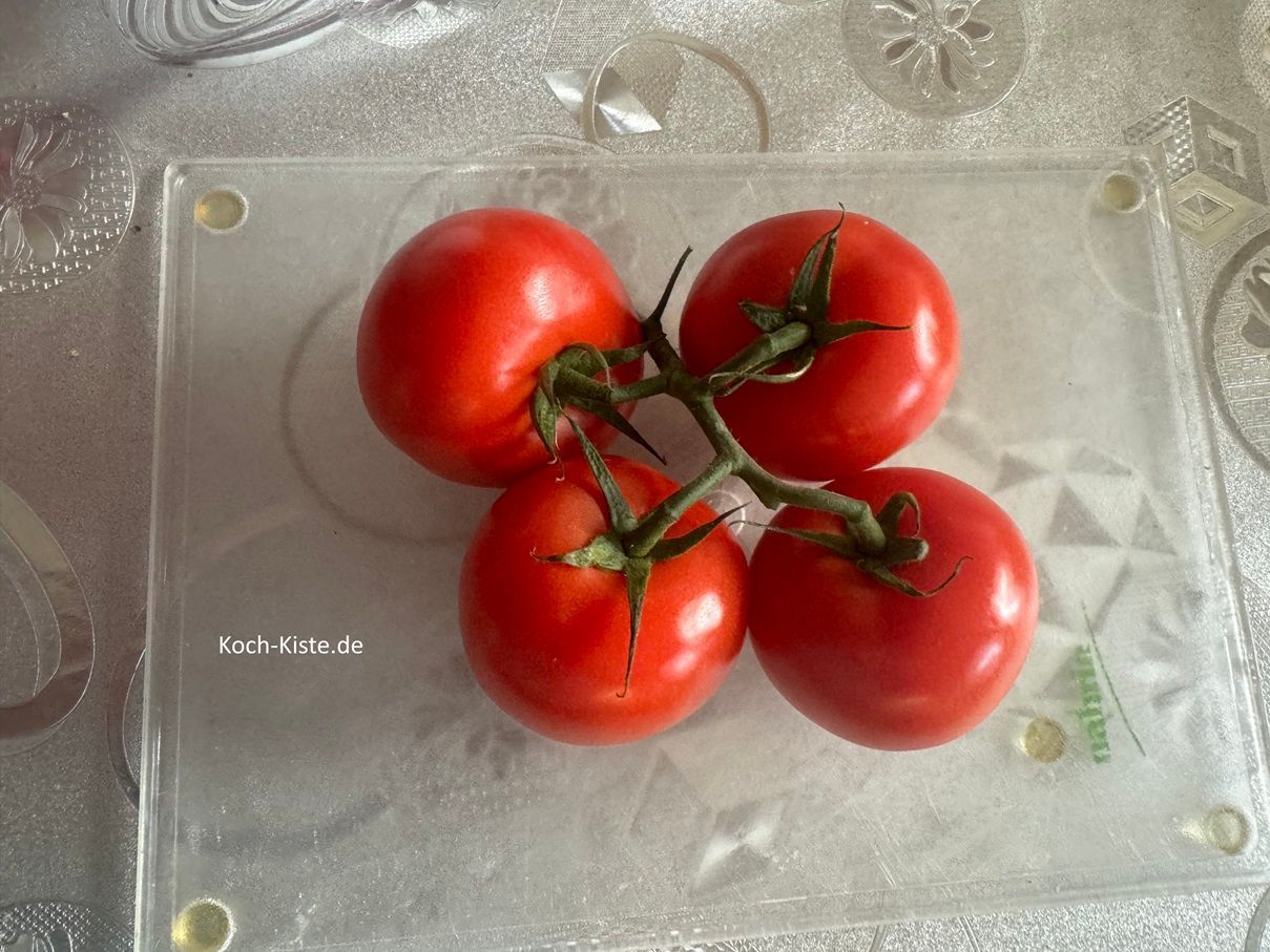 lege die abgespülten Tomaten auf das Schneidebrett und ziehe die Tomaten von den Stielen ab.
