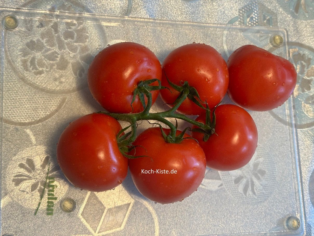 beginne damit die Strauchtomaten unter kaltem, fließendem Wasser abzuspülen und auf das Schneidebrett zu legen. Danach befreist Du die Tomaten vom Strauch und entfernst den Kelch