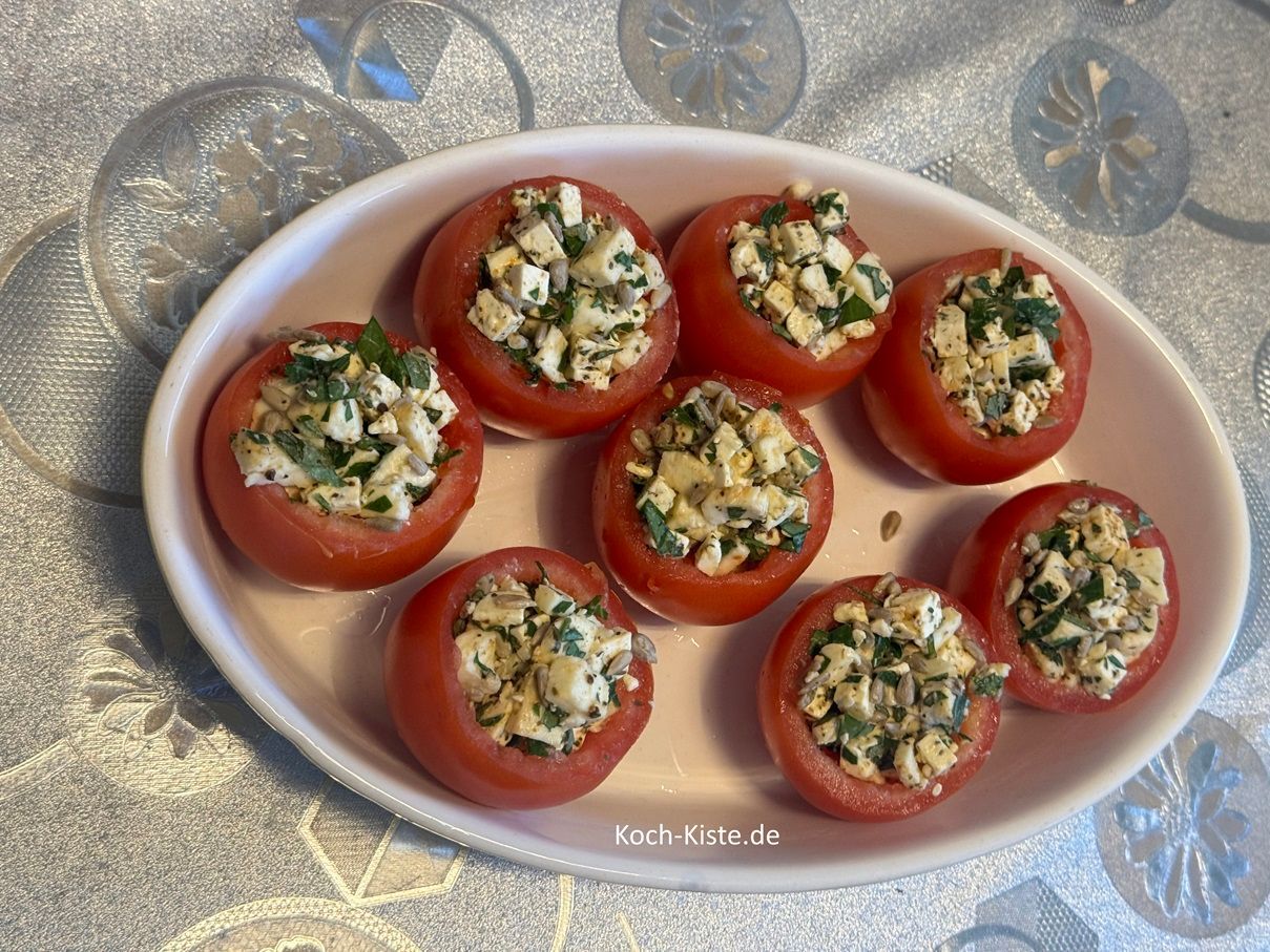 setze die Tomaten hinein und fülle sie dann mit Hilfe eines Teelöffels. Danach gebe die Auflaufform auf die mittlere Schiene des Backofens und backe die Tomaten 15 Minuten