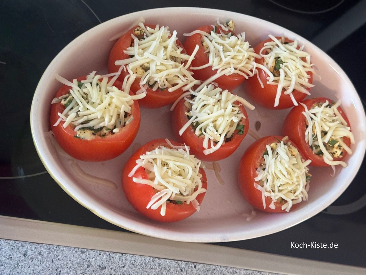 ziehe Dir Küchenhandschuhe an, nehme die Auflaufform aus dem Backofen und stelle sie auf den Herd. Nun verteile 50 g geeriebenen Käse auf die Tomaten . Dann schiebe die Auflaufform wieder in den Backofen und backe die Tomaten noch mal 10 Minuten