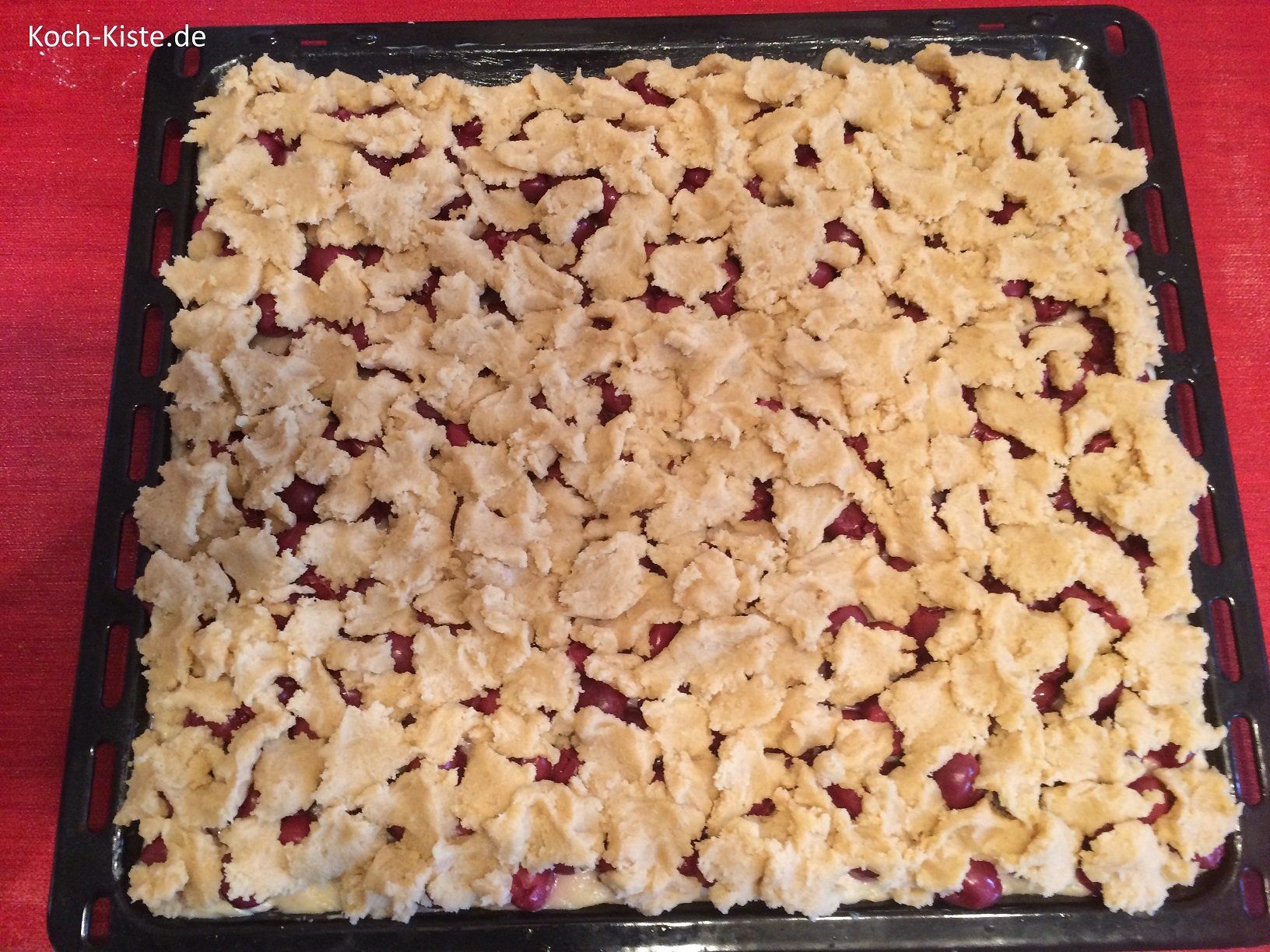 Streusselteig-Abrisse gleichmäßig auf den Kirschen verteilen