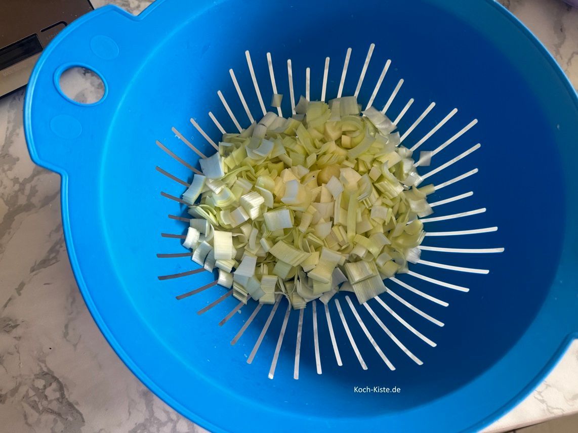 gebe die Porreestücke in ein Küchensieb und spüle sie unter kaltem, fließendem Wasser ab.