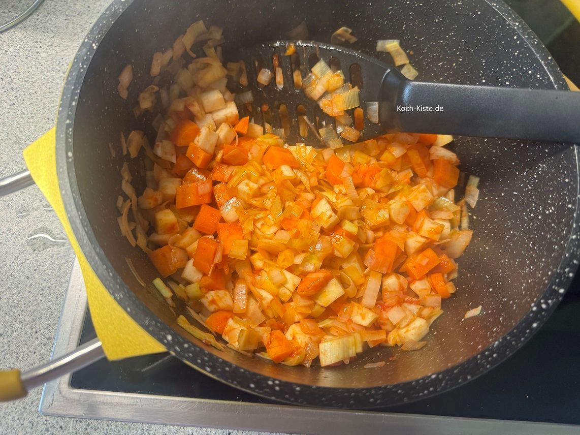 verteile mit dem Pfannenwender das Tomatenmark gleichmäßig und brate es kurz an