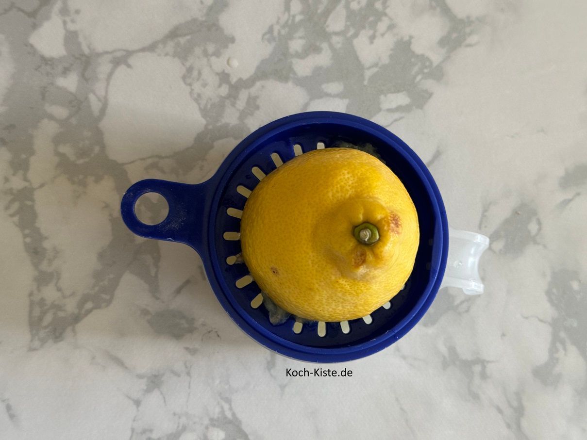 halbiere die Zitrone und setze eine Zitronenhälfte auf die Zitronenpresse. Presse den Saft heraus und beträufel die Fischwürfel damit.