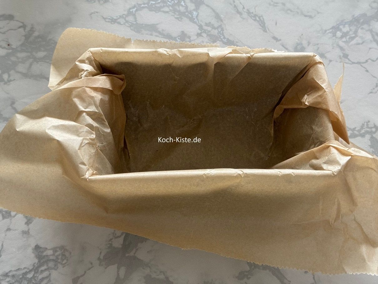 nehme einen Bogen Backpapier und lege damit die kleine Kastenform aus