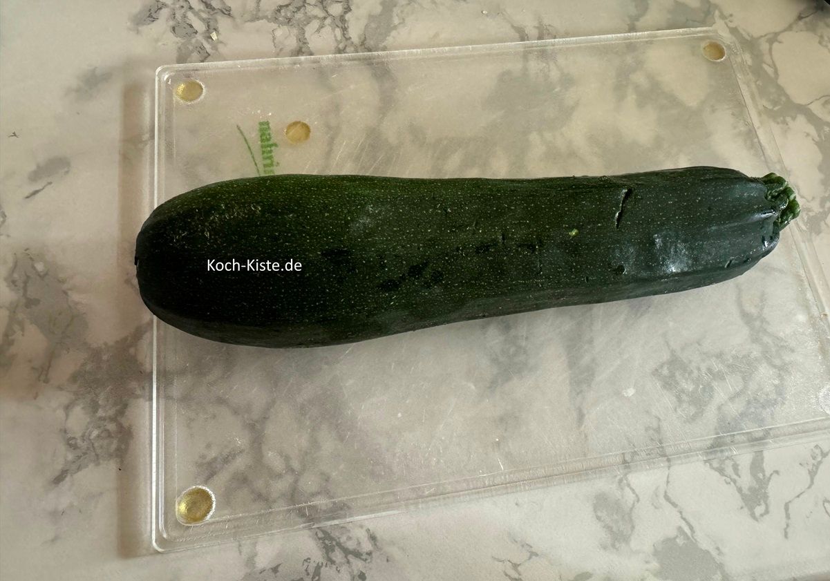 Lege die Zucchini auf das Schneidebrett und schneide oben und unten ein kleines Stück weg.