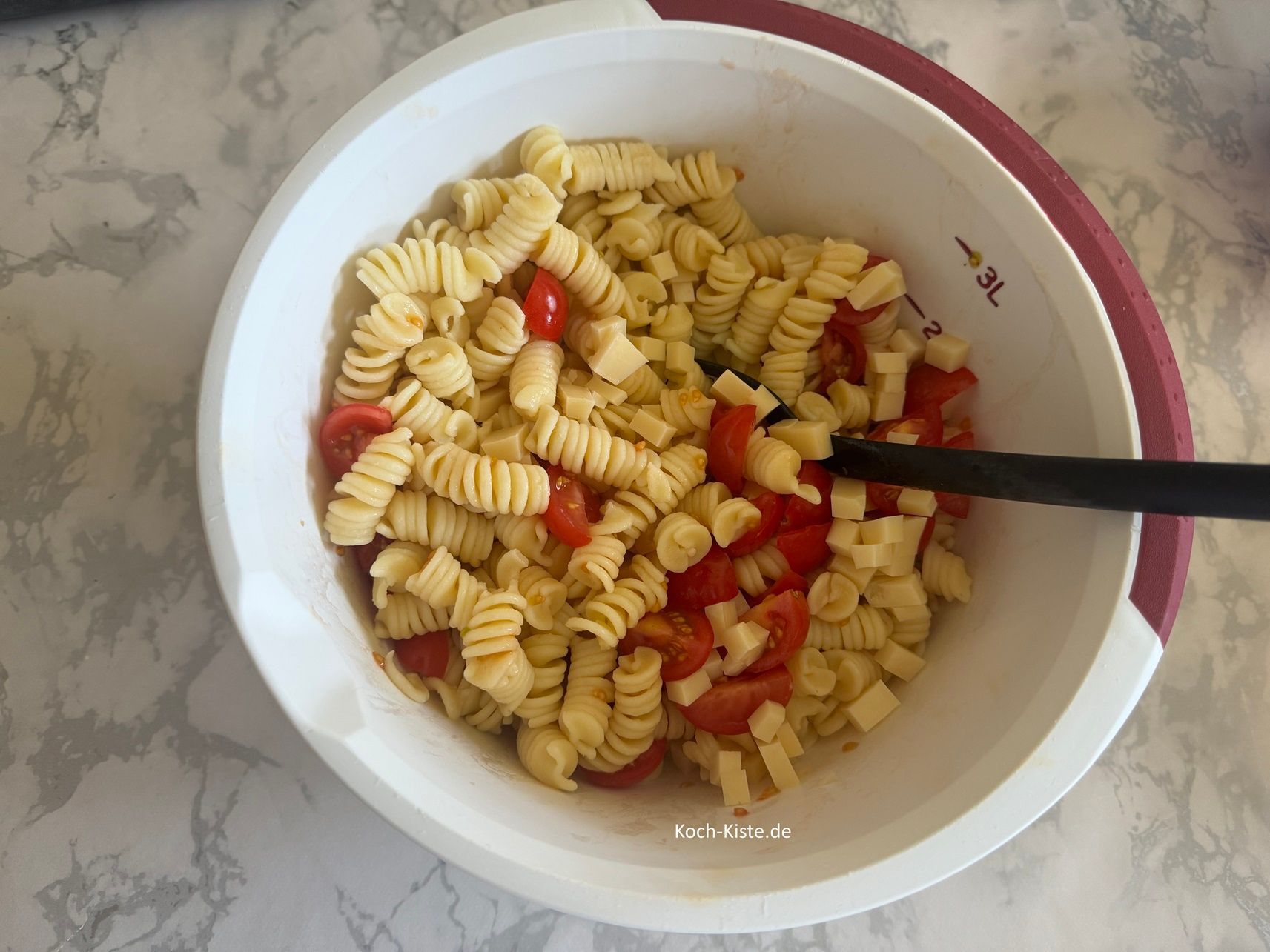 Hinweis: meine Schüssel war zum verrühren zu klein :-) Also die Nudeln in eine Rührschüssel umgefüllt. Dann kippe die Käsestücke und Tomatenviertel mit in die Rührschüssel