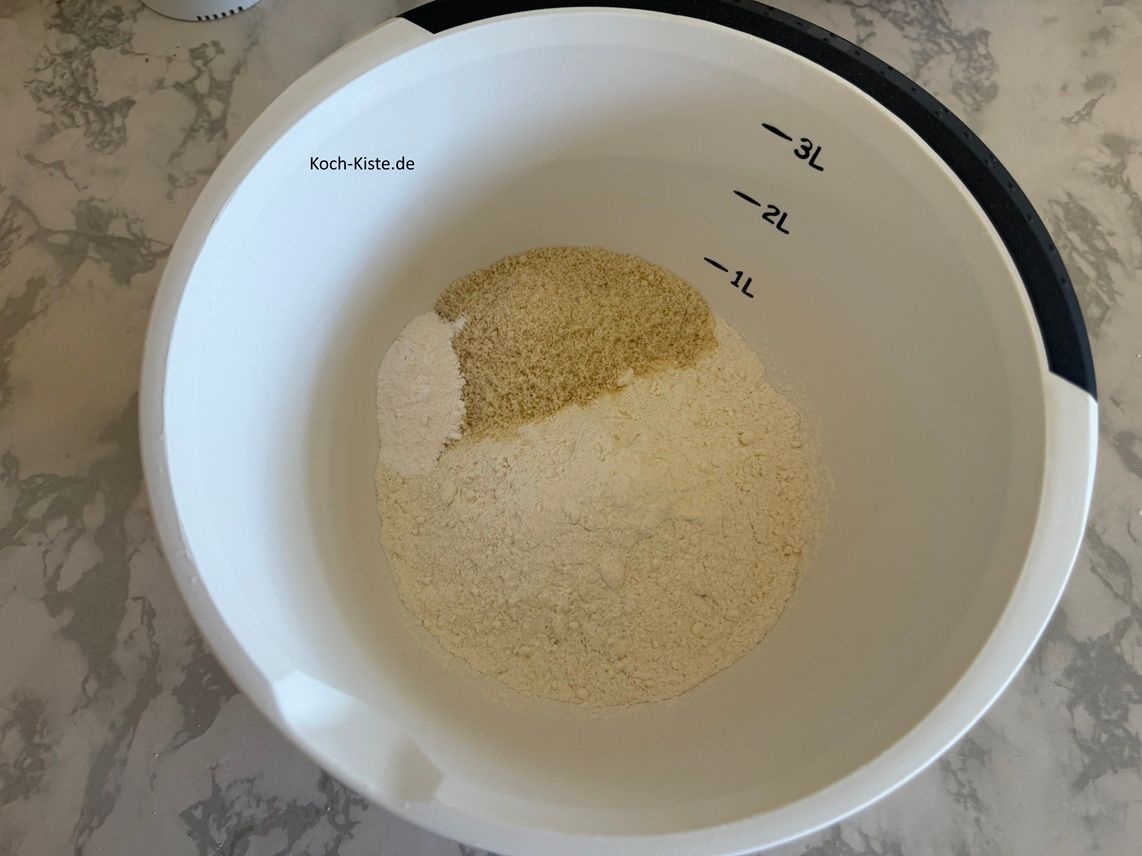 stelle die 2 Rührschüssel auf die Küchenwaage - auf 0 und wiege 300 g Dinkelmehl ab. Stelle die Küchenwaage erneut auf 0 und wiege 50 g Kokosraspel ab. Vermische beide Zutaten mit einem Esslöffel